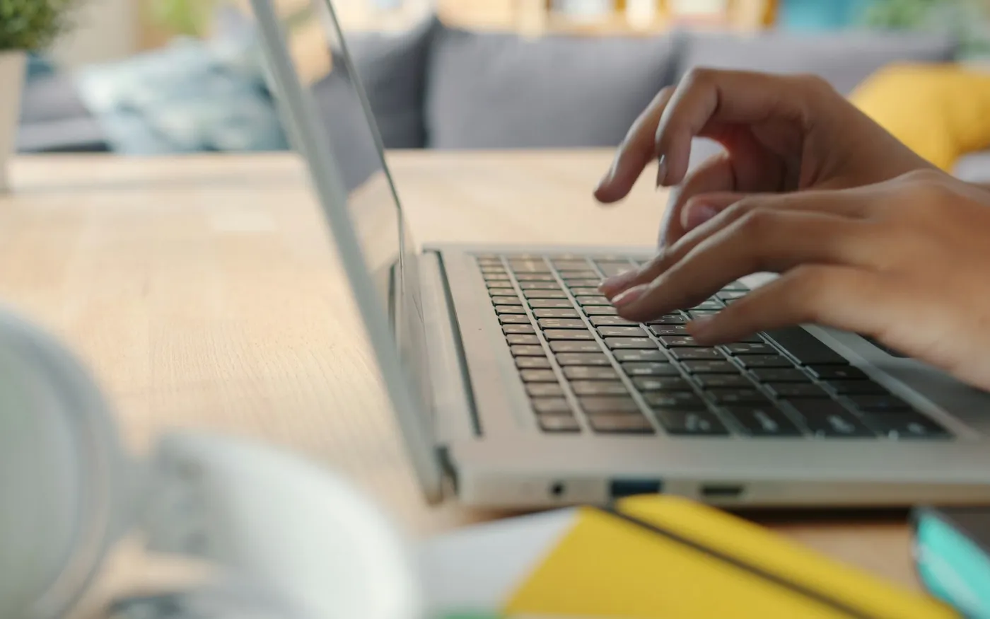 Hands typing on a laptop keyboard at a wooden desk