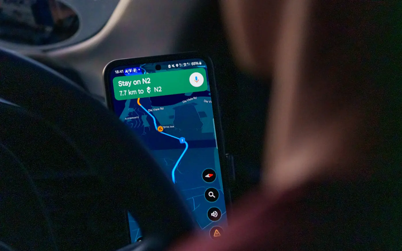 A smartphone showing a navigation route, held up inside a car