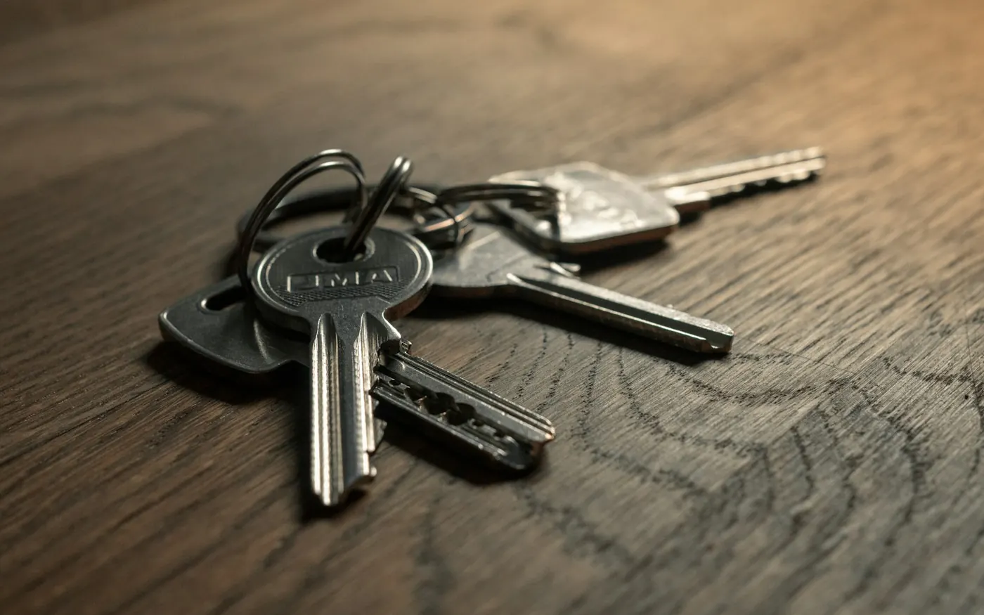 A ring of house and padlock keys on a dark wooden table