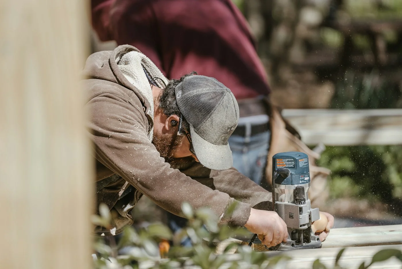 A tradesperson using a power tool on a wooden deck